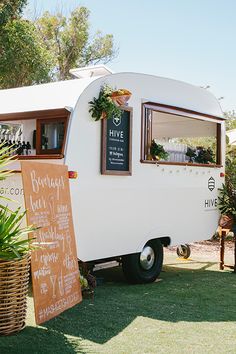 an old camper is decorated with plants and chalkboard signs for the menus