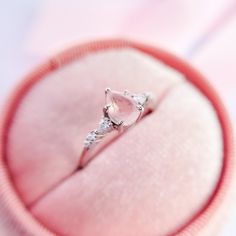 an engagement ring in a pink velvet box with diamonds on the side and inside it