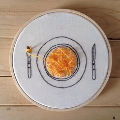 an embroidered plate with a fork and knife on it, next to a piece of orange peel