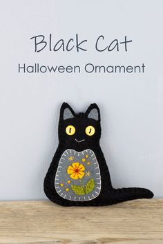 a black cat sitting on top of a wooden table next to a sign that says cat ornament