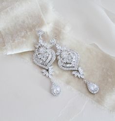 "Beautiful long statement earrings feature an Art Deco style with delicate details. Created with luxurious Swarovski Pure Brilliance stones set in a metal setting and embellished with a lovely crystal halo. Finished with Swarovski pearls. You can also choose a cz teardrop instead of pearls. Earrings measure 3\" x 1\" Available in 3 finishes Matching pieces: https://www.etsy.com/listing/475999054/rose-gold-bridal-bracelet-crystal https://www.etsy.com/listing/489501555/rose-gold-necklace-bridal-ne Opulent Silver Earrings For Wedding, Glamorous Crystal Chandelier Earrings With Elegant Design, Ornate Wedding Diamond Drop Earrings, Diamond Chandelier Drop Earrings With Intricate Design, Diamond Chandelier Earrings With Intricate Design, Elegant Long Drop Chandelier Earrings With Sparkling Stones, Glamorous Drop Chandelier Earrings With Elegant Design, Elegant Crystal Chandelier Earrings, Luxury Dangle Linear Earrings For Wedding