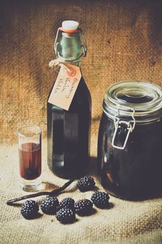 a bottle of syrup and some blackberries next to it