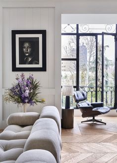 a living room filled with furniture next to a window covered in glass and framed pictures