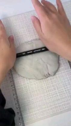 a person is using a pencil to draw on a marble object with white paper and black marker