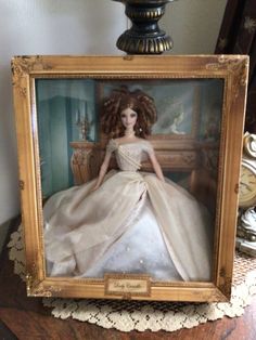 a doll is sitting in a frame on a table