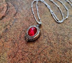 This incredibly beautiful locket opens from bottom to top and fastens with a delicate latch. The locket is set with a stunning vintage West German ruby red glass gem. Small intricate details are etched on the locket. The burnished silver finish gives it an authentic vintage look. The locket is 25mm in size. It hangs on a stainless steel beaded satellite chain finished with the lobster claw clasp. The chain is 45cm + 5cm long. Red Victorian Necklace For Anniversary, Red Necklace With Vintage Charm As A Gift, Red Vintage Charm Necklace For Gift, Red Necklace With Vintage Charm For Gift, Antique Red Jewelry For Gifts, Red Victorian Engraved Necklace, Victorian Red Engraved Necklace, Red Locket Necklace For Jewelry Making, Antique Jewelry With Lobster Clasp For Gift