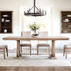 a dining room table with chairs and a chandelier hanging from the ceiling above it