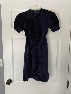 "Very cool and unusual navy blue 1940's mini dress in a velvet almost corduroy texture. Covered buttons up the center front and a built in belt. Likely a young tween size originally but could be worn by a petit adult. Short puffed sleeves. The only problem spot I'm seeing is on the center front on one button and the fabric next to it - just a couple rubbed/worn spots. Being sold as is Womens XXS 32\" chest 30\" waist 36\" hips 11\" shoulder to waist 20.5\" waist to hem 12\" back shoulders" Velvet Navy Mini Dress, Blue Velvet Mini Dress, Navy Vintage Dresses With Buttons, Indie Blue Velvet Dress, 1940s Velvet Dress, Velour Dress H&m, Corduroy Texture, 1930 Velvet Dress, 40s Outfits