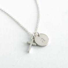 Commemorate a baptism, first communion or another special date with this tiny cross necklace personalized with a dainty initial charm. This cross necklace features a sterling silver cross that measures approximately 1/2 inch, along with a sterling silver round charm that can be engraved with one initial. The chain is also sterling silver and is available in lengths for 15 - 20 inches. Your new necklace will come in a box, ready for gift giving. More Christian jewelry https://www.etsy.com/shop/Au Personalized Dainty Jewelry For First Communion, Silver Cross Pendant Necklace For Birthday, Dainty Personalized Jewelry For First Communion, Personalized Sterling Silver Jewelry For Baptism, Minimalist Personalized Cross Necklace, Silver Cross Necklaces With Name Detail, Personalized Dainty Cross Necklace, Classic Cross Necklace For Baptism, Silver Name Necklace With Cross Pendant