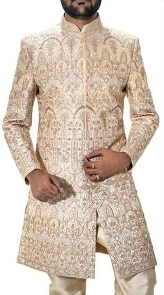 Elevate your wedding style with our meticulously crafted Beige Silk Sherwani 2Pc (Jacket pyjama) It has beige color churidar as bottom made from dupion fabric.This exquisite garment is a true embodiment of timeless elegance and sophistication. The heavy embroidery, intricately designed, adds a regal touch to your groom's ensemble. The attention to detail is evident in every stitch, making this sherwani a perfect choice for your special day. The sherwani is complemented by a matching churidar pajama, creating a seamless and stylish look that exudes grace and charm. When you choose our Beige Silk Sherwani, you're choosing a classic piece that will make you stand out on your wedding day, leaving a lasting impression on everyone in attendance. It's not just a garment; it's a statement of your Tuxedo Suit For Men, Sherwani For Groom, Indian Groom Dress, Groom And Groomsmen Suits, Sherwani For Men Wedding, Green Tuxedo, Sherwani Groom, Groom Wedding Dress, Traditional Jacket