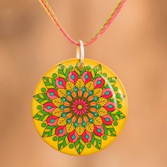 a yellow necklace with a colorful flower design hanging from it's side on a string