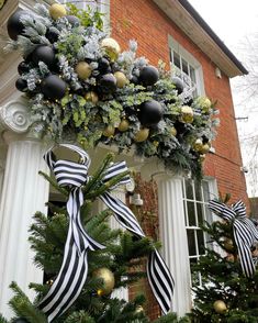 a decorated christmas tree in front of a house with black and gold ornaments on it