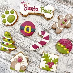 decorated cookies are arranged on a table with the words santa paws written in large letters