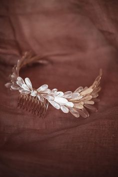 a hair comb with leaves on it sitting on a brown cloth covered tablecloth,