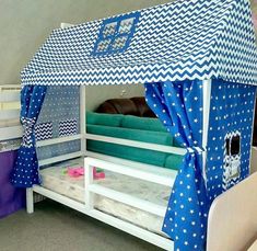 a bunk bed with blue and white curtains on it's sides is in the middle of a room