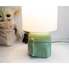 a baby yoda lamp sitting next to a stuffed animal