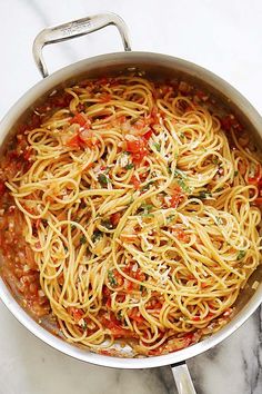 a pan filled with pasta and sauce on top of a marble counter