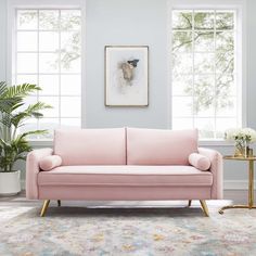 a living room with a pink couch and potted plants