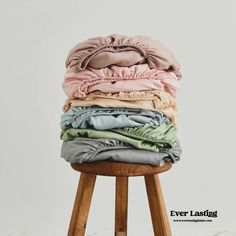 a stack of folded clothes sitting on top of a wooden stool