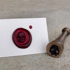 a wax stamp with a skull on it next to a piece of paper that has been cut out