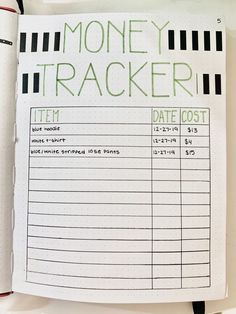 a notepad with money tracker written in green ink on top of a white table