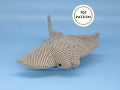 a knitted toy shark laying on top of a blue background with the text pattern below it