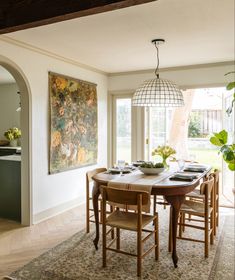 the dining room table is set with place settings for six people and has a large painting on the wall