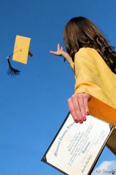 a woman holding a certificate in front of a graduation cap and flying through the air