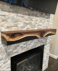 a stone fireplace with a wooden mantle and tv above it