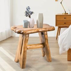 a wooden table with three vases on top of it next to a night stand