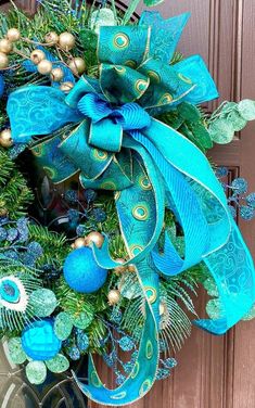 a wreath with blue and green decorations hanging on a door