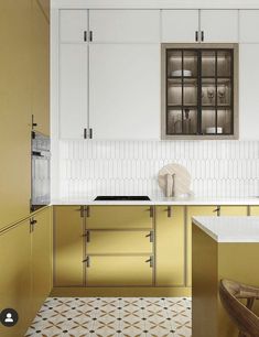 a kitchen with white cabinets and gold counter tops