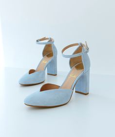 a pair of blue high heeled shoes sitting on top of a white surface