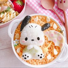 a bowl filled with rice and topped with an animal figurine next to another bowl full of food