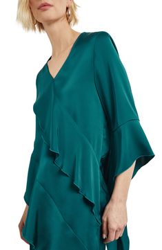 Asymmetric ruffles romance this V-neck top crafted from luxe satin and framed by cascading flutter sleeves. 12" length to 28" length V-neck Three-quarter sleeves 100% polyester Hand wash, dry flat Imported Draped Blouse With Ruffles, Elegant Draped Ruffle Blouse, Elegant Ruffled V-neck Blouse, Elegant V-neck Ruffle Blouse, Elegant Ruffle Hem Top For Evening, Elegant Evening Top With Ruffle Hem, Elegant Evening Tops With Ruffle Hem, Elegant Evening Blouse With Ruffle Sleeves, Elegant Ruffle Sleeve Evening Blouse