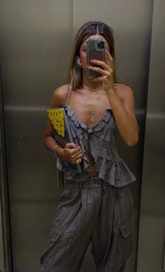 a woman taking a selfie in front of an elevator with her cell phone up to her face