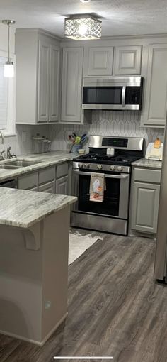 an empty kitchen with stainless steel appliances and wood flooring is pictured in this image