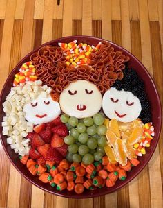 a plate filled with fruit and vegetables on top of a wooden table in the shape of faces