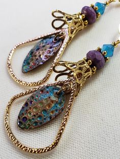 Hand-Painted Earrings. The centerpiece of these earrings are the beautiful hand-painted on copper with resin charms made by Washington State artist Kristi. I accented them with rounded triangle connectors, vintage brass bead caps, purple faceted Czech glass beads and turquoise Swarovski crystal bicone beads. These earrings are 3 inches long including the pure brass round lever back closures. One Of A Kind I can send it gift wrapped (free of charge), if requested. Artsy Copper Drop Earrings, Artsy Copper Jewelry With Matching Earrings, Bohemian Gold Earrings With Patina, Gold Bohemian Earrings With Patina, Hand Painted Gold Metal Jewelry, Artistic Hand Painted Copper Earrings, Bohemian Enamel Earrings Nickel-free, Bohemian Enamel Earrings Nickel Free, Soldered Enamel Drop Earrings