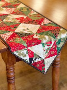 a wooden table with a red and green patchwork quilt on it's edge