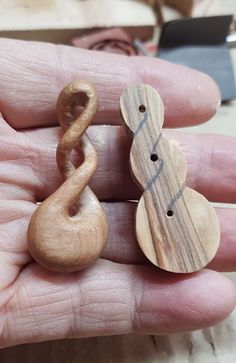 two wooden buttons in the palm of someone's hand, one with a treble