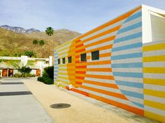 a colorful building with palm trees and mountains in the backgroung behind it