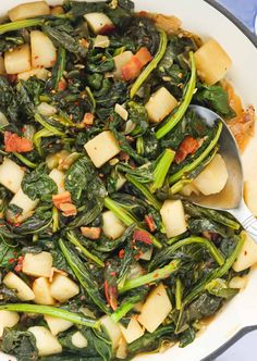 spinach and potatoes in a skillet with spoons on the side