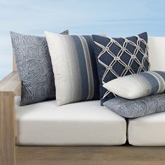 a white couch with pillows on top of it and a wooden table in the background