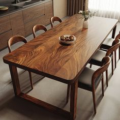 a wooden table with chairs around it and a bowl of fruit on the dining room table