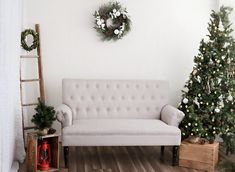 a white couch sitting next to a christmas tree on top of a hard wood floor