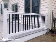 a white porch with black railings on the side of a house next to a fence