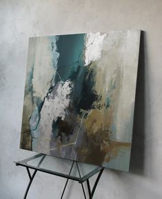 an abstract painting sitting on top of a metal stand