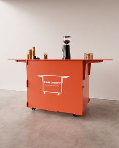 an orange cart with spices on it in a white walled area next to a wall