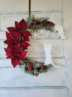 two christmas wreaths with poinsettia and deer on them hanging from the side of a door